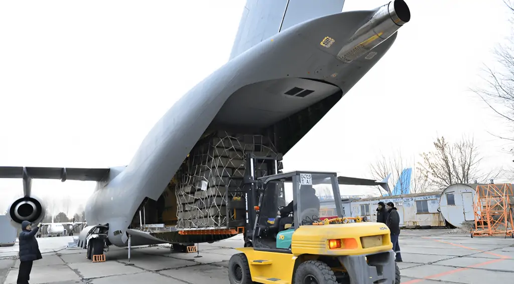 The Antonov An-178 is a state-of-the-art cargo aircraft with a remarkable cargo hold capacity that can accommodate large loads of cargo. In this image, a loader car is seen transporting pallets into the aircraft's cargo hold, which is spacious enough to accommodate a variety of cargo sizes and types. The loader car's efficiency in loading the pallets onto the aircraft is impressive, highlighting the aircraft's adaptability to various loading methods. The Antonov An-178's cargo hold is specifically designed to enable quick and safe loading and unloading of cargo, making it a preferred choice for air freight operators worldwide. The pallets are safely secured, ready to be transported to their destination, underscoring the aircraft's reliability and versatility in cargo transportation.