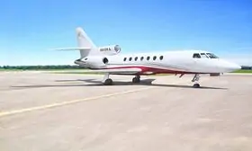 The DASSAULT FALCON 50 is Standing majestically on the apron, with its impressive wingspan, and powerful engines.